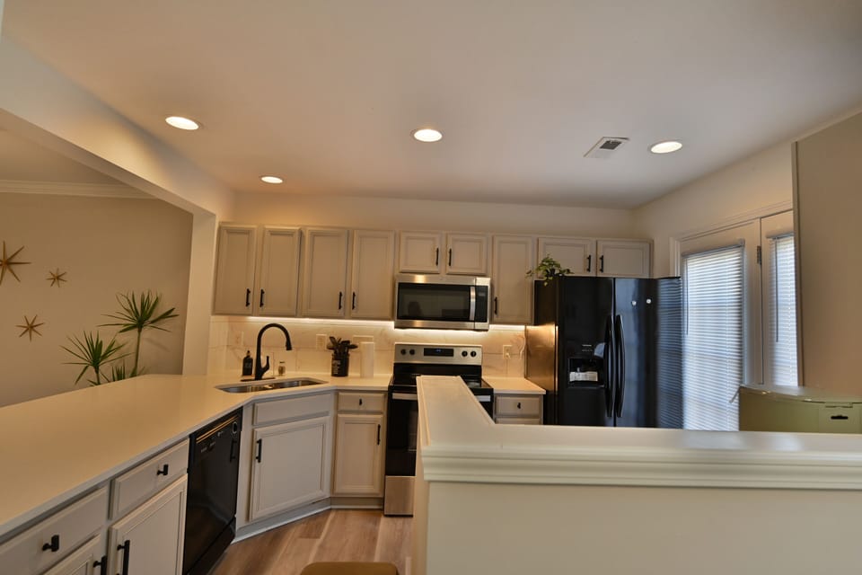 Modern kitchen with grey cabinets, black appliances, and marble backsplash