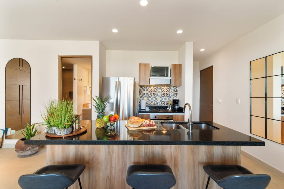 Kitchen with fridge, blender, coffee machine, and island—ocean views.