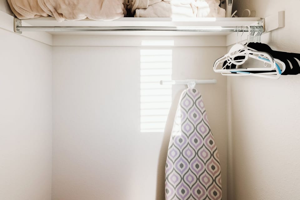 Large closet area with an ironing board and iron.