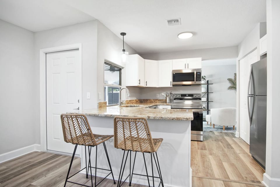 Modern kitchen with granite island, bar stools & stainless appliances