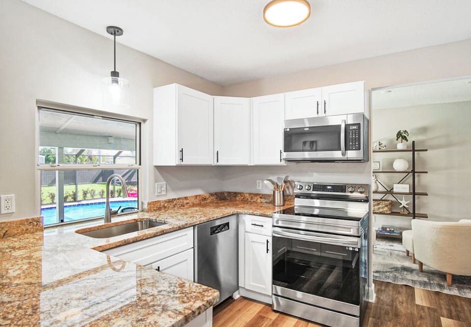 Fully stocked kitchen with pool views, stainless stove & dishwasher