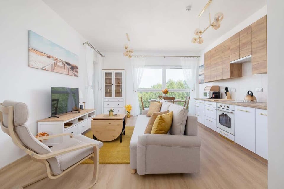 Another angle of the main living space, showing harmonious integration of kitchen, dining, and lounging areas in a sunny, open layout.