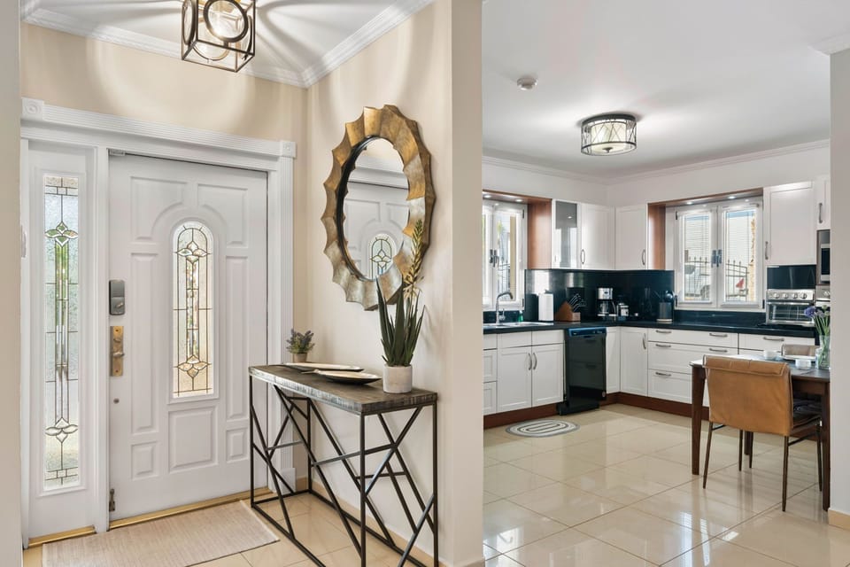 - Welcoming entryway with elegant details, including a decorative mirror and stylish console table - Natural light enhances the warmth of the space, leading into a modern kitchen - A perfect blend of sophistication and comfort greets you at the door