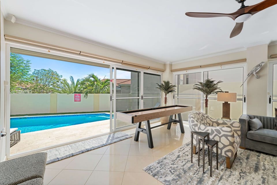 - Enjoy endless fun with a shuffleboard table in this bright sunroom overlooking the pool - Floor-to-ceiling windows invite abundant natural light, enhancing the vibrant atmosphere - Perfect blend of relaxation and entertainment in a stylish space