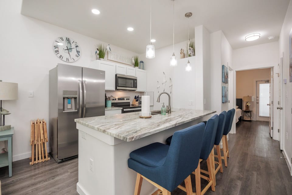 Your modern kitchen invites culinary adventures with marble countertops, stainless steel appliances, and comfortable island seating for memorable meals together.
