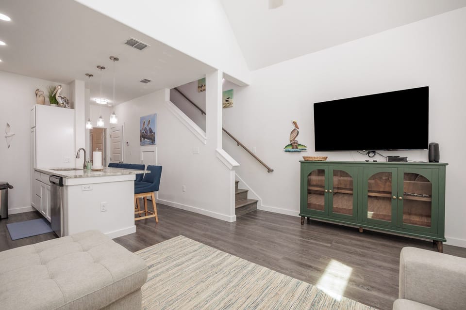 Relax in your bright, open living space where modern comfort meets coastal charm with sleek kitchen and cozy seating.