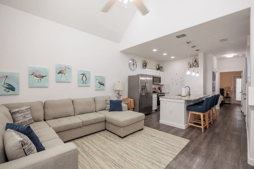 Your bright, open-concept space blends coastal charm with modern comfort—relax on the spacious sectional while enjoying vaulted ceilings and stylish bird artwork.