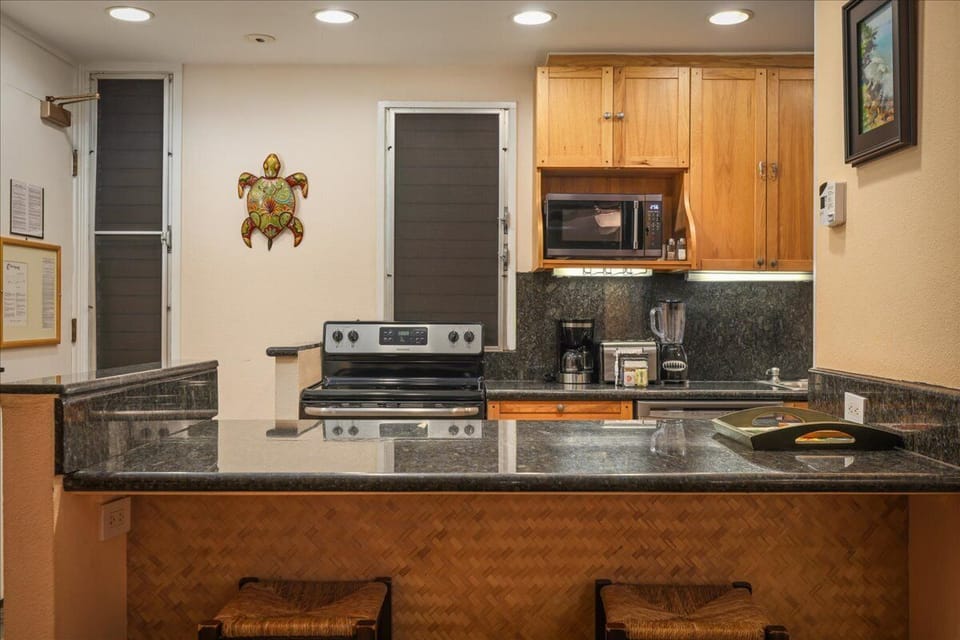Your fully-equipped kitchen features granite countertops, stainless appliances, and tropical-inspired decor. Gather around the island with seating for casual meals or coffee before your beach adventures.
