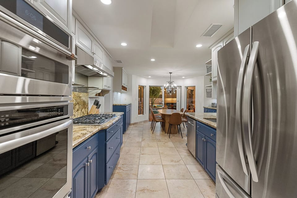 Open kitchen with double ovens, stainless appliances & scenic outdoor views.
