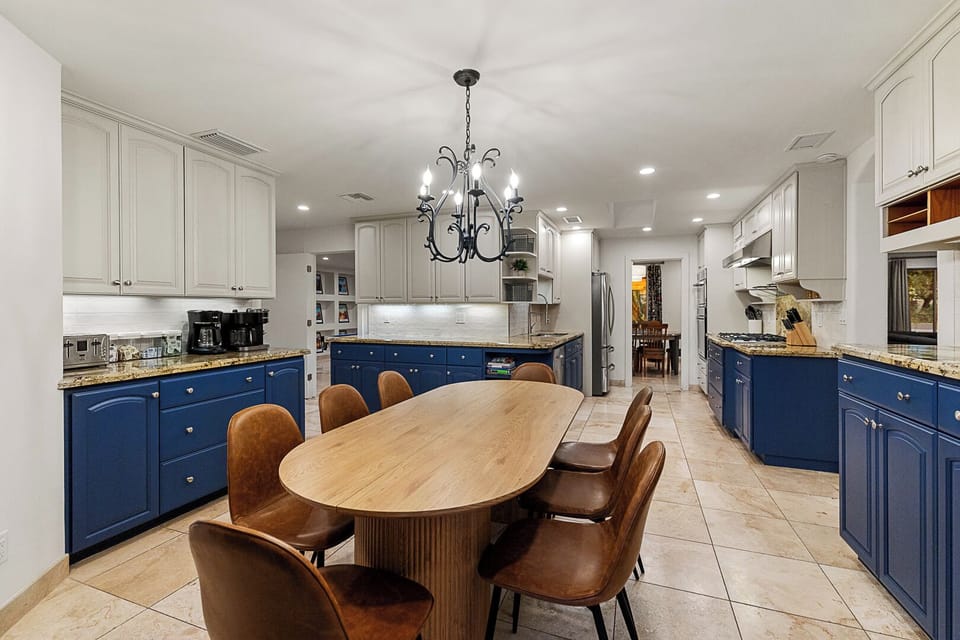 Chef's kitchen with navy cabinets, granite counters & custom table for meals.
