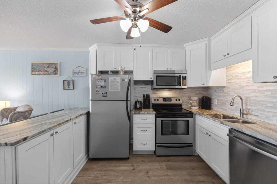 Kitchen - Kitchen with appliances including a stove, refrigerator, microwave, and dishwasher along with cookware for preparing meals.