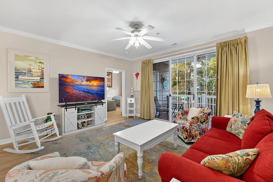 Living Room - Relax in the bright and comfortable living room with plenty of seating and multiple TVs — perfect for unwinding after a day of golf or beach fun.
