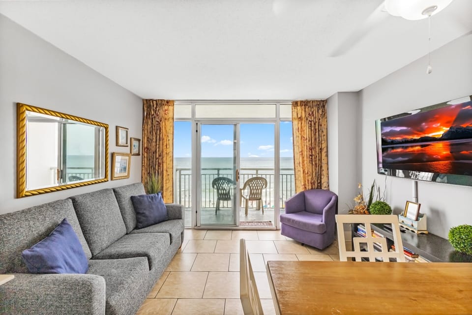 Living Room - Relax in the open living area with plenty of seating and three flat-screen TVs — ideal for family time or unwinding after beach days.