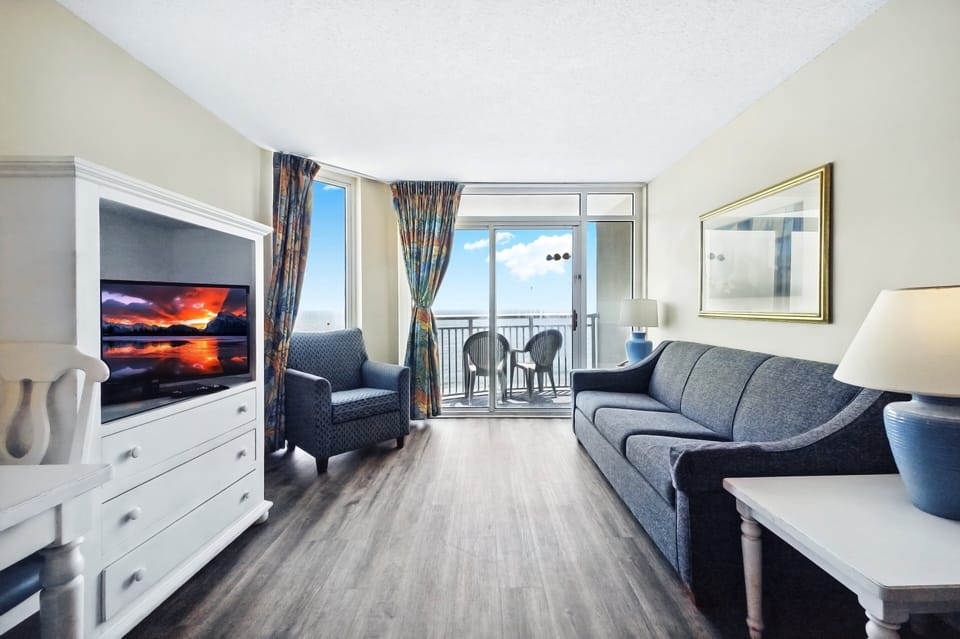 Living Room - Comfortable living room with plenty of seating and multiple flat‑screen TVs — ideal for relaxing with family or friends after a day on the beach.