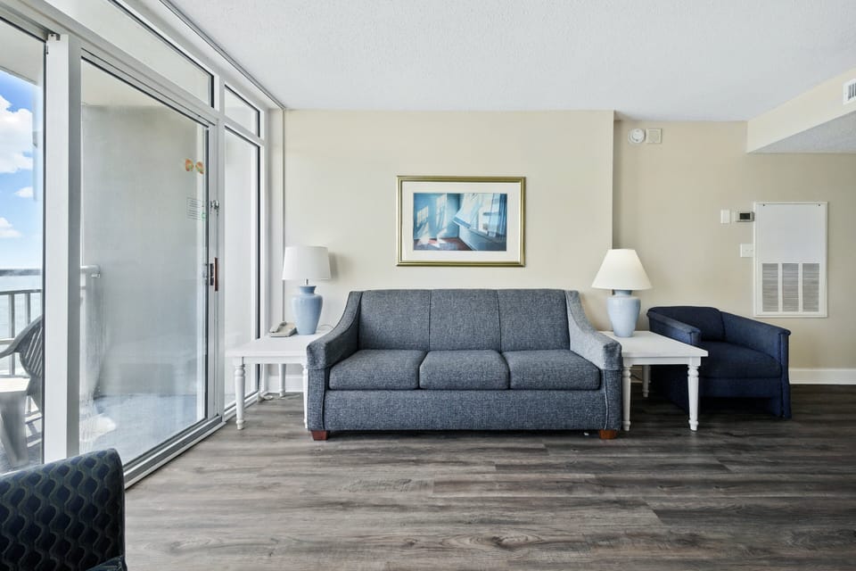 Living Room - Comfortable living room with plenty of seating and multiple flat‑screen TVs — ideal for relaxing with family or friends after a day on the beach.