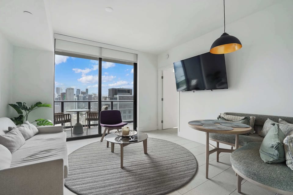 Natural light fills the room, opening onto a private balcony with city views
