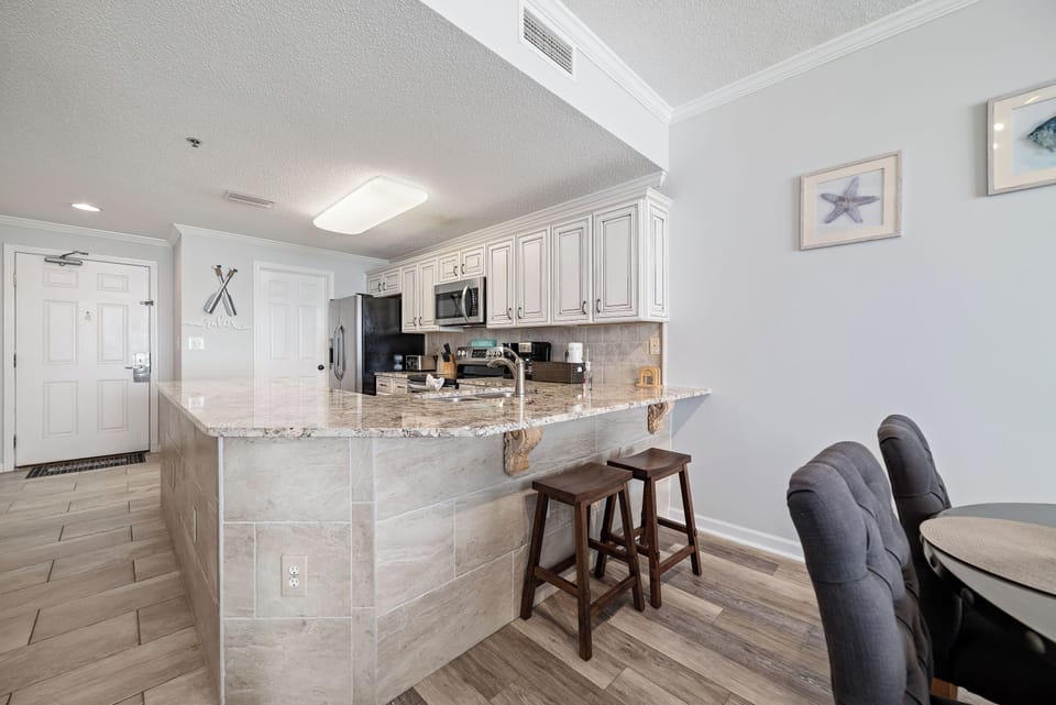This beautifully designed kitchen boasts a spacious island with a flawless countertop and stylish stools, creating a natural hub within the home.