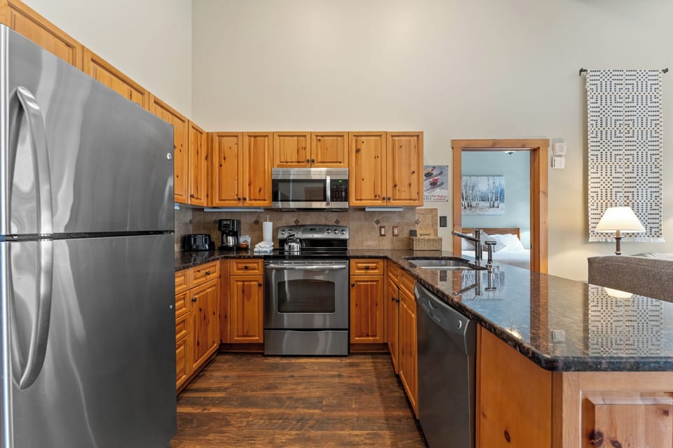 Your fully equipped kitchen features granite counters, stainless appliances, and warm wood cabinets—perfect for preparing meals during your mountain getaway.
