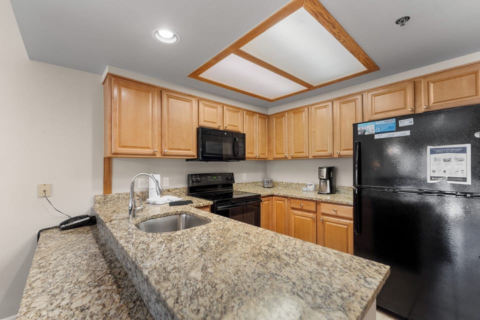 Your fully equipped kitchen features granite counters, warm wood cabinets, and modern appliances for preparing home-cooked meals during your stay.