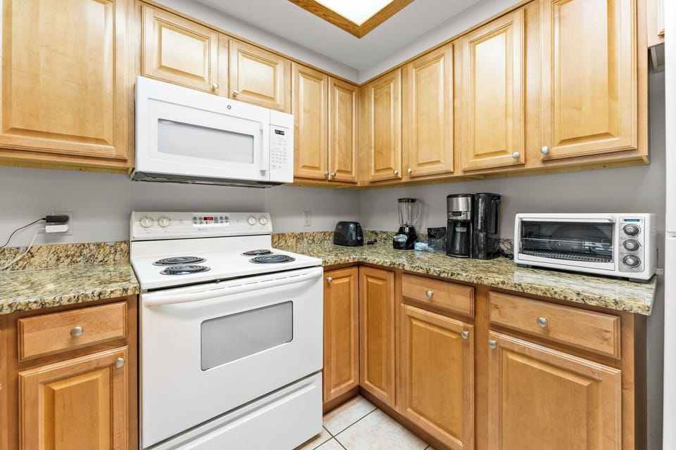 Your fully equipped kitchen features warm wood cabinets, granite countertops, and essential appliances for preparing delicious meals during your stay.