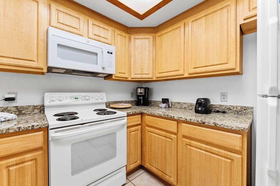Your fully equipped kitchen features granite countertops, honey-colored cabinetry, and modern appliances for preparing memorable meals.