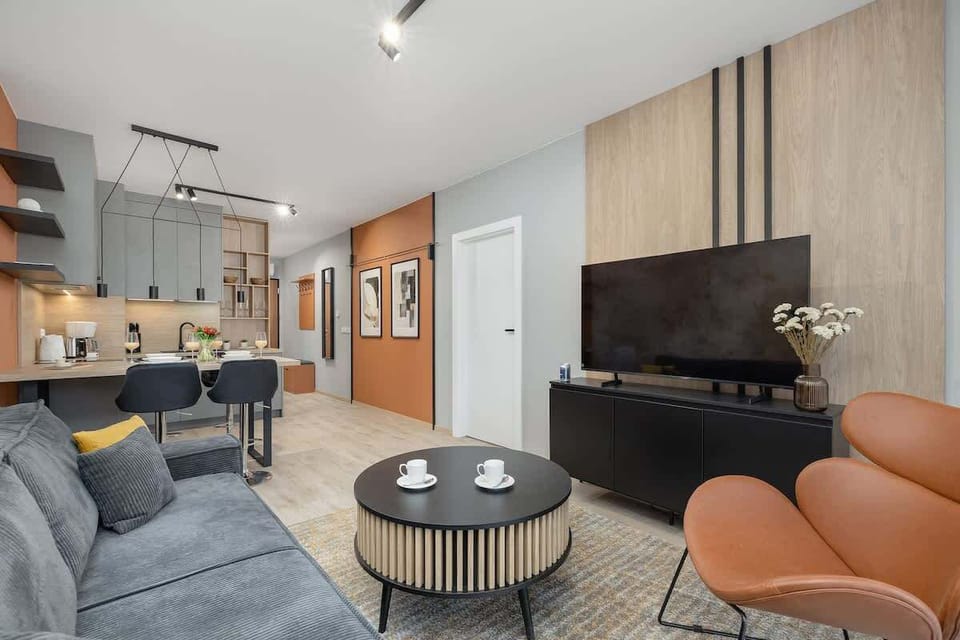 Open-plan living area with a gray sofa, coffee table, and kitchen in the background.