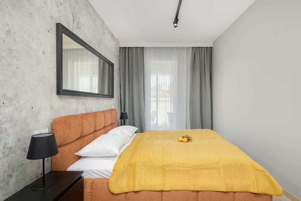 Bright bedroom with yellow bedding, a gray accent wall, and sheer curtains.