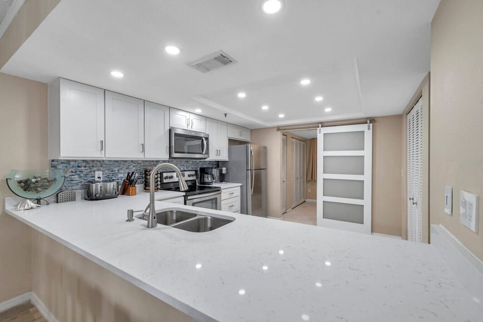 Sleek white kitchen w/ modern finishes, ample counter space, and a clean, airy feel.