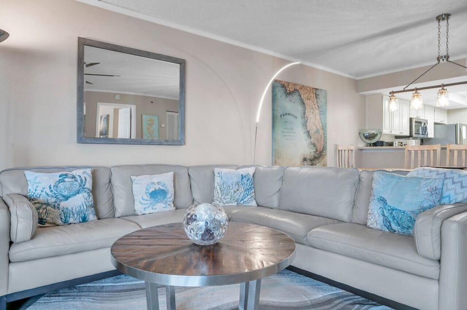 Cozy seating area w/ textured pillows, round coffee table, and calming coastal décor.