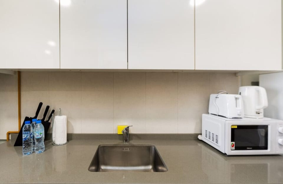 A sleek and fully equipped kitchen with all the essentials, including a microwave, electric kettle, and a full set of knives—perfect for preparing meals during your stay.