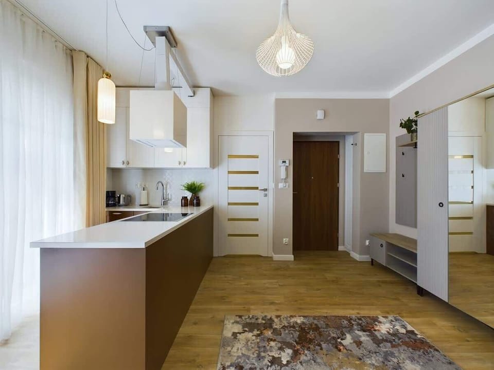 A compact kitchen with light cabinetry and a small dining table next to large windows.