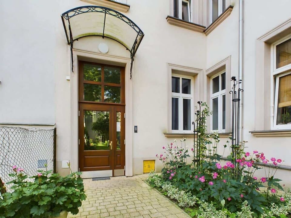 A view of the building’s exterior and entrance, with plants and a charming old-style doorway.