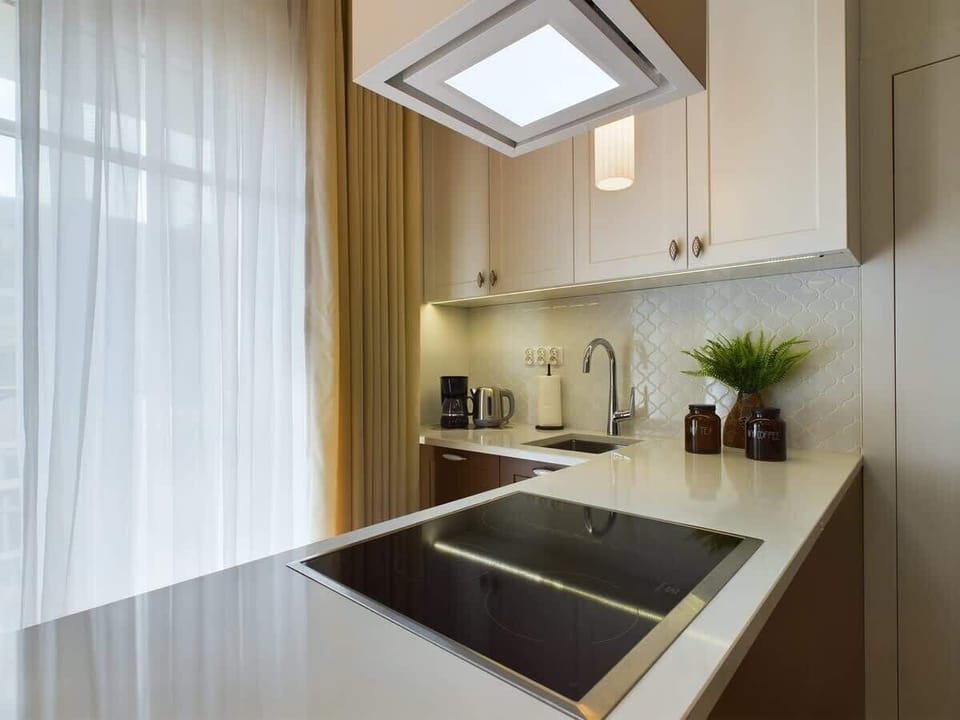A modern kitchen corner with wood and black details, including a sink and extractor fan.