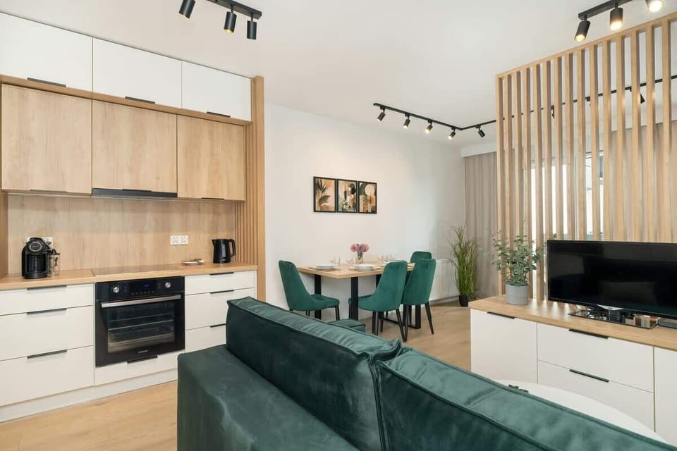 Kitchen designed with white and wooden cabinetry, black appliances, and discreet overhead lighting.