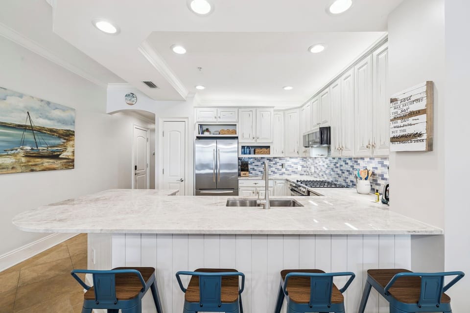 Your gourmet kitchen features marble counters, stainless appliances, and coastal charm with seating for five at the breakfast bar.