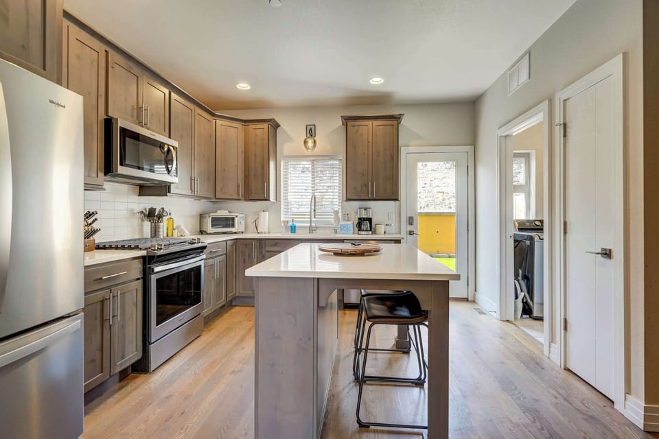 Streamlined kitchen with a central island, modern cabinetry, and bar seating that invites casual meals or conversation. Clean lines, warm floors, and open sightlines make it easy to cook, serve, and stay connected while you do.
