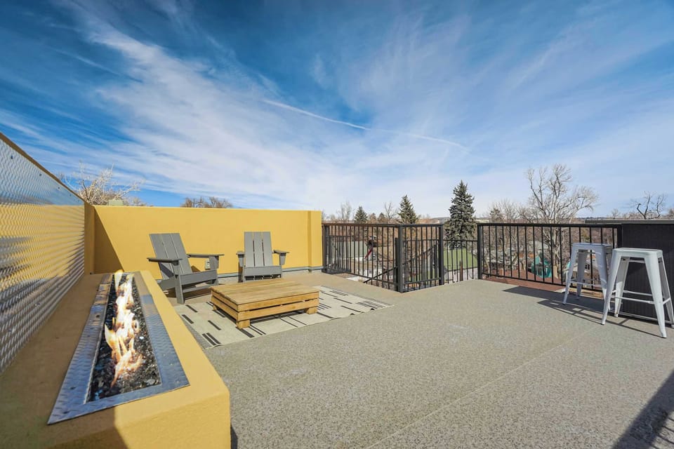 Open rooftop deck with sleek seating and a long fire feature sets the scene for breezy afternoons and glowing evenings. Stretch out under wide skies, gather around the flame, and enjoy the open-air layout framed by clean lines and city views.