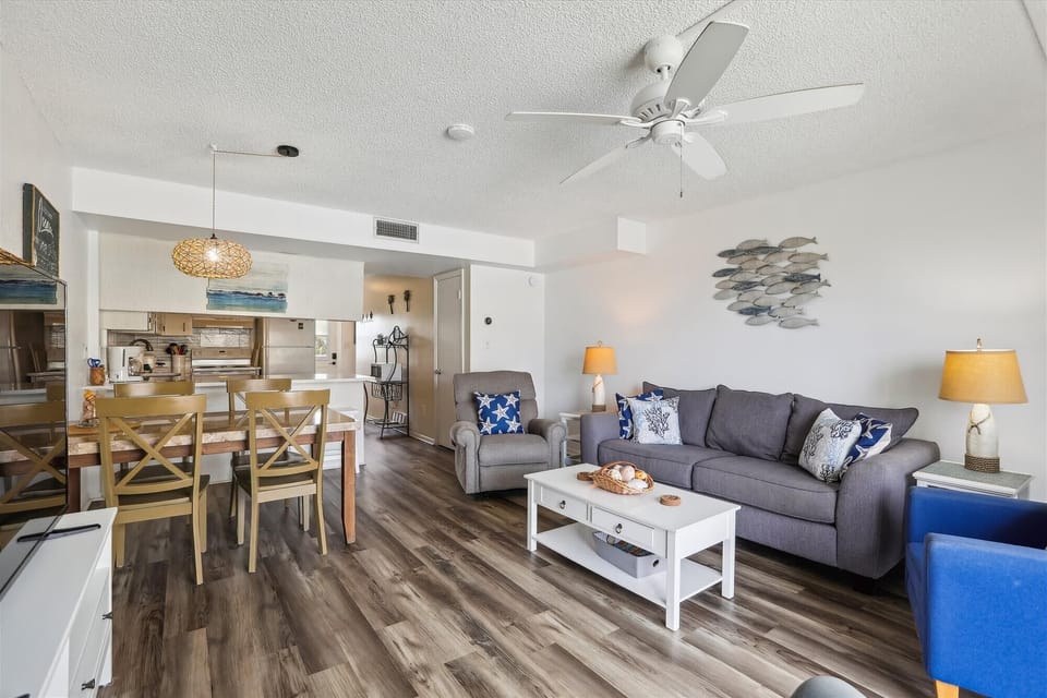 - Beach condo living room with modern furniture and pool views  
- Bright open space with kitchen access and balcony seating  
- Airbnb stay near St Augustine Beach for families and couples  
