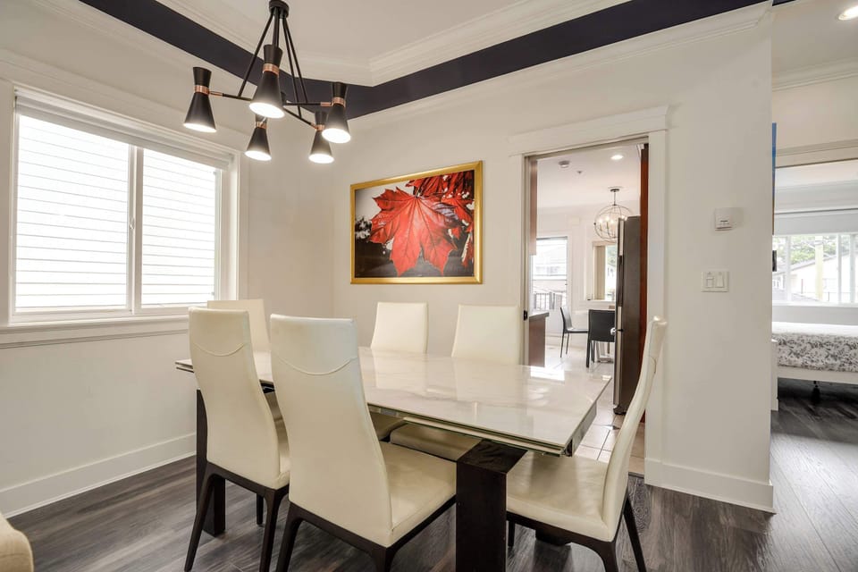 Modern dining room with a sleek marble table and comfortable seating, highlighted by a vibrant artwork and chic chandelier.