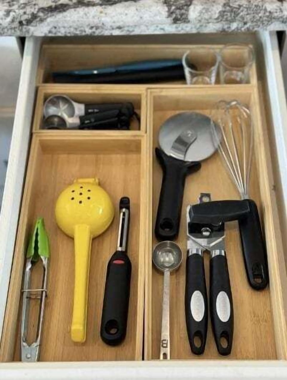 Kitchen drawer with utensils including can opener and serving tools