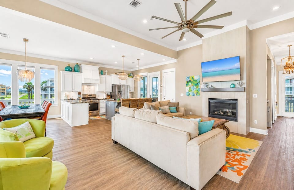 Spacious open-concept living room with sectional sofa, ceiling fan, and large windows