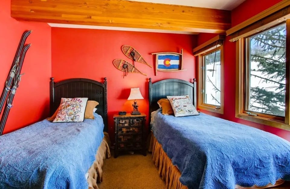 The cozy guest bedroom is thoughtfully decorated with vibrant colors and rustic ski-themed accents, offering twin beds that invite restful nights after a day on the slopes.
