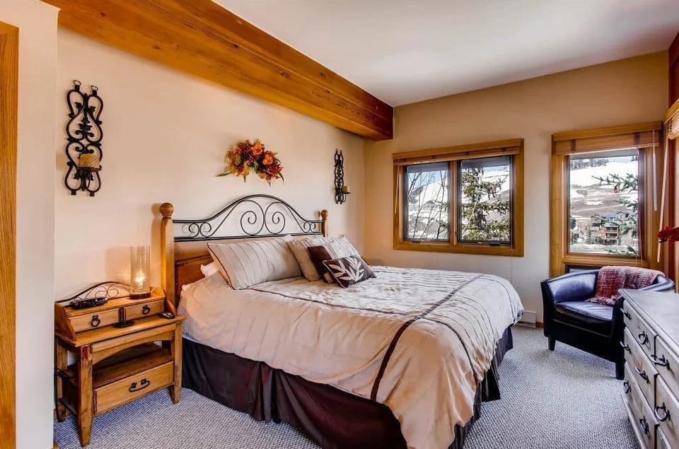 The tranquil master bedroom provides a peaceful retreat, featuring plush bedding and large windows that frame the stunning mountain landscape, perfect for unwinding after a day of adventure.