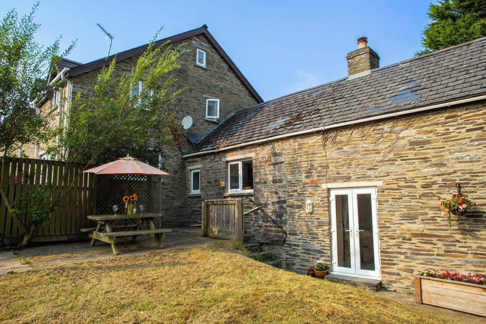 Patio area with picnic bench and parasol next to the lawn area
