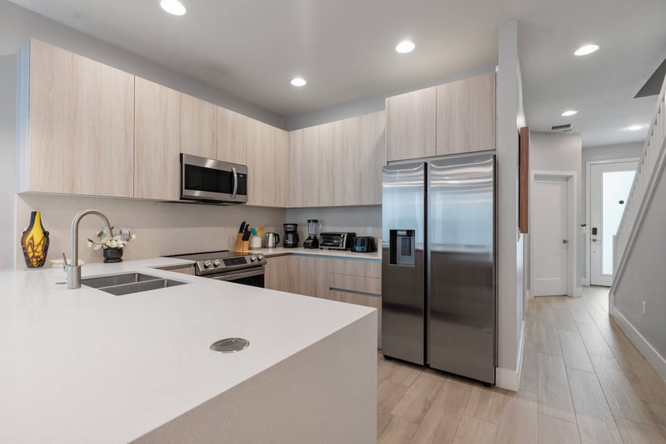 This stylish kitchen boasts light wood cabinetry and a spacious island, ideal for casual meals or meal prep. With stainless steel appliances and modern fixtures, it invites you to unleash your culinary creativity.