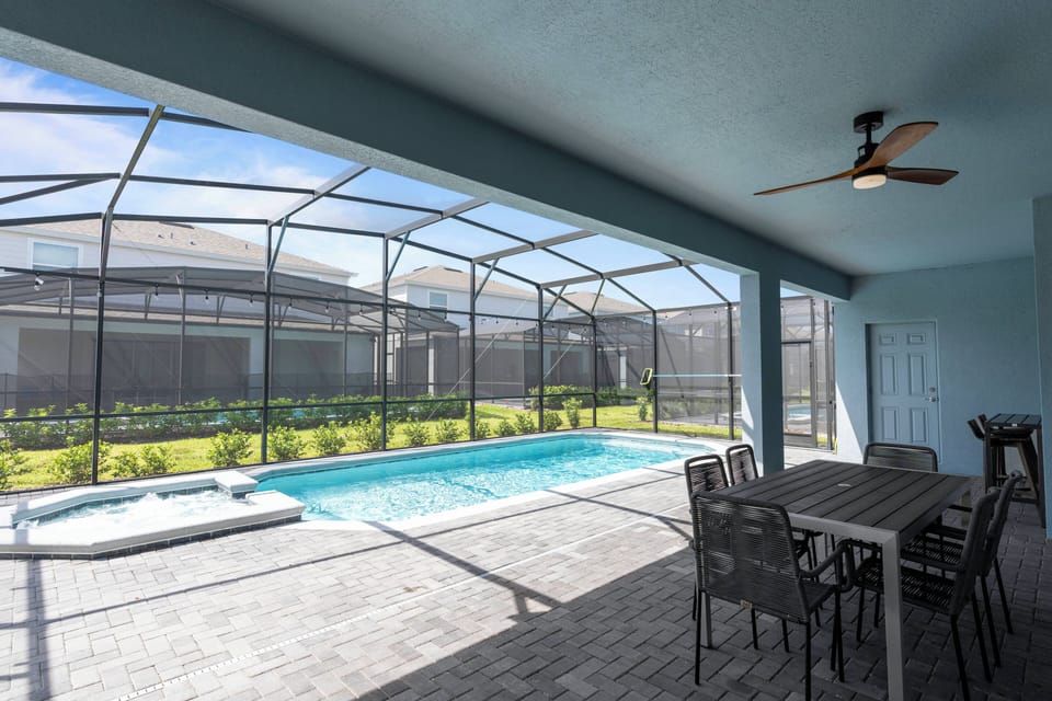 Welcome to your sunlit oasis with a sparkling pool and spacious dining area, ideal for al fresco meals. Enjoy a tranquil atmosphere in the screened enclosure, complemented by a sleek ceiling fan and refreshing neutral tones.
