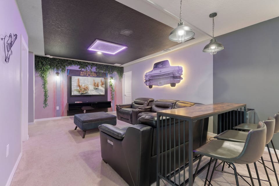 Step into a stylish entertainment area featuring a sleek, dark ceiling that enhances the cozy ambiance. The inviting sectional sofa is perfect for movie nights, while the modern bar seating adds a fun touch for casual gatherings.