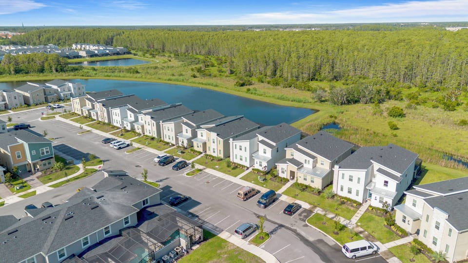Experience tranquil scenery from your vacation home, where sleek homes line a peaceful pond. Enjoy the natural beauty of lush greenery and open skies that invite you to unwind and explore the surrounding landscape.