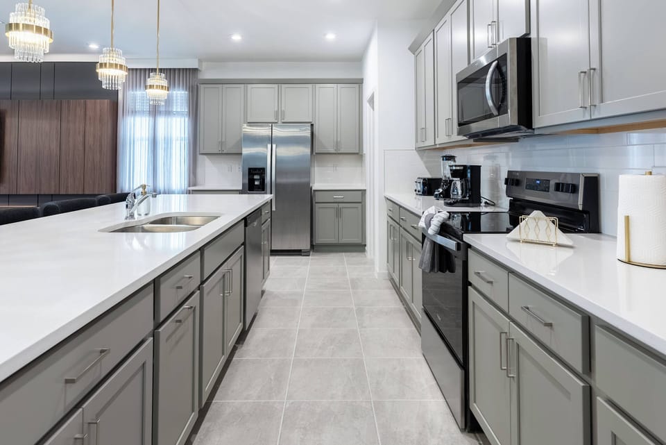Welcome to a spacious kitchen with sleek grey cabinetry and an open layout that inspires culinary creativity. Enjoy plenty of prep space on the large island, modern appliances, and inviting pendant lighting for a stylish ambiance.