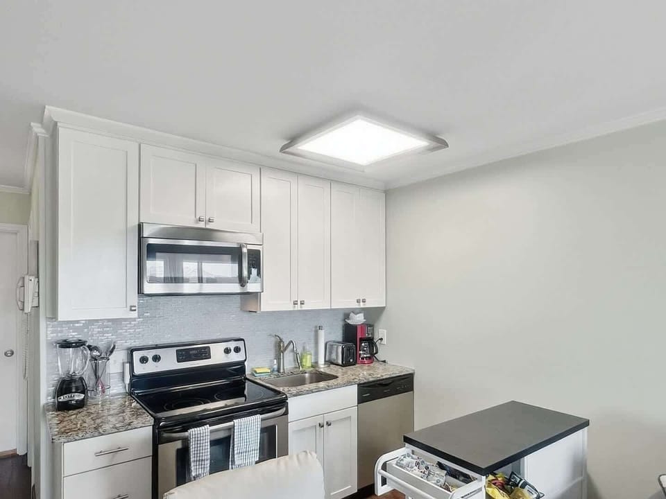 A modern, well-equipped kitchen with white cabinetry and granite countertops.